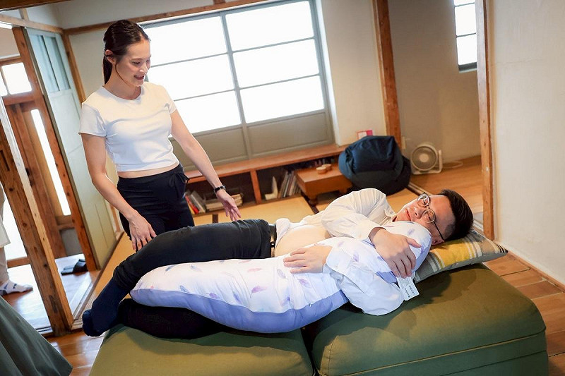 賴瑞隆(右)穿「孕婦裝」臥躺使用孕哺枕。   圖：賴瑞隆辦公室/提供