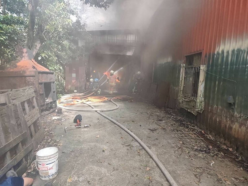 新北市汐止區一棟鐵皮工廠24日上午發生火警，現場冒出大量黑煙，消防局獲報趕往布設水線搶救，2名員工吸入些許濃煙送醫。（新北市消防局提供）中央社記者曹亞沿傳真　114年11月24日   