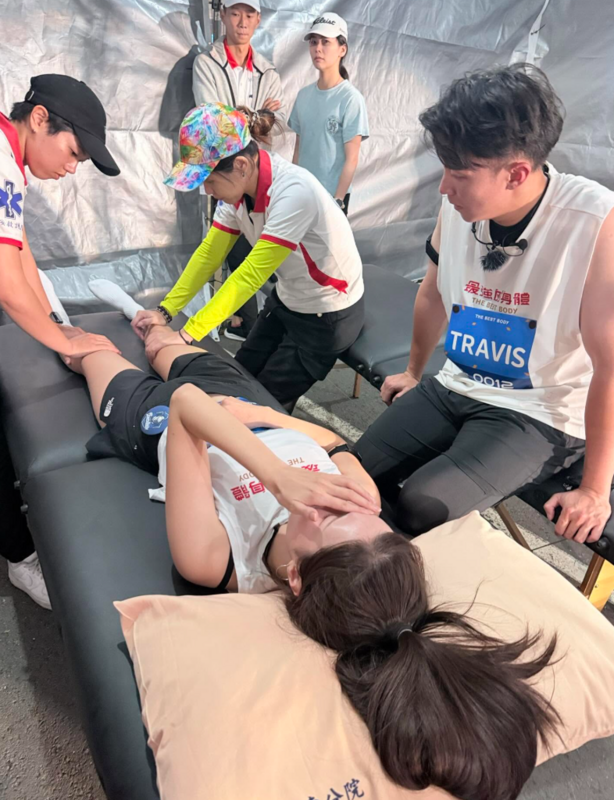 南珉貞躺在床上，2名醫護人員在幫她按摩小腿，而南珉貞則痛到用手遮住臉。   圖：翻攝自南珉貞Threads