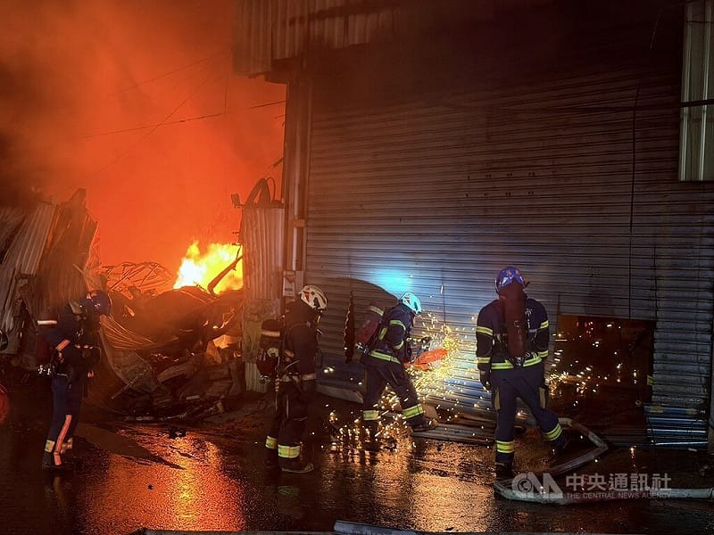 新北市八里區龍米路一段某木工工廠7日清晨突起火燃燒，由於火勢猛烈，濃煙直竄，共延燒3間工廠，消防人員切割破壞鐵皮廠房大門進行灌救。    圖/中用社（翻攝照片） 