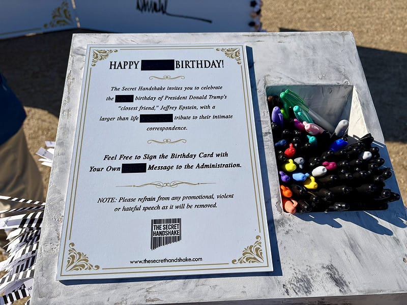 裝置旁的說明牌鼓勵民眾在卡片上簽名，並「向川普政府表達祝福」，諷刺意味濃厚。 圖:翻攝自X帳號@joeflood