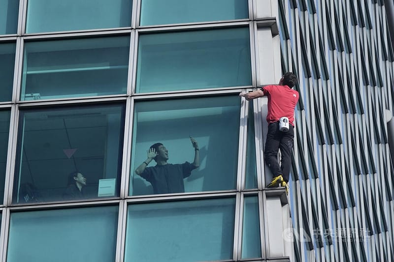 美國自由攀岩好手霍諾德徒手攀登台北101大樓，一名民眾在大樓玻璃窗內開心拍攝。中央社記者徐肇昌攝 115年1月25日&nbsp;&nbsp;&nbsp;