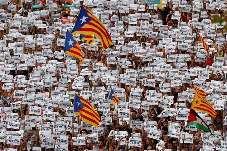 支持獨立運動的群眾揮舞獨立旗幟，手持標語，要求西班牙政府釋放兩位遭到羈押的獨立運動領袖。   圖：達志影像/路透社