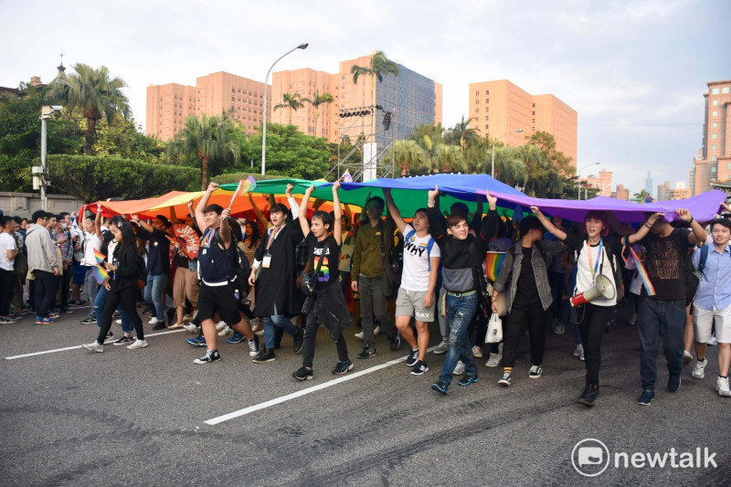 第15屆台灣同志遊行，義工和民眾一起手持巨幅彩虹旗，由舞台前方展開。   圖：黃堃睿/提供