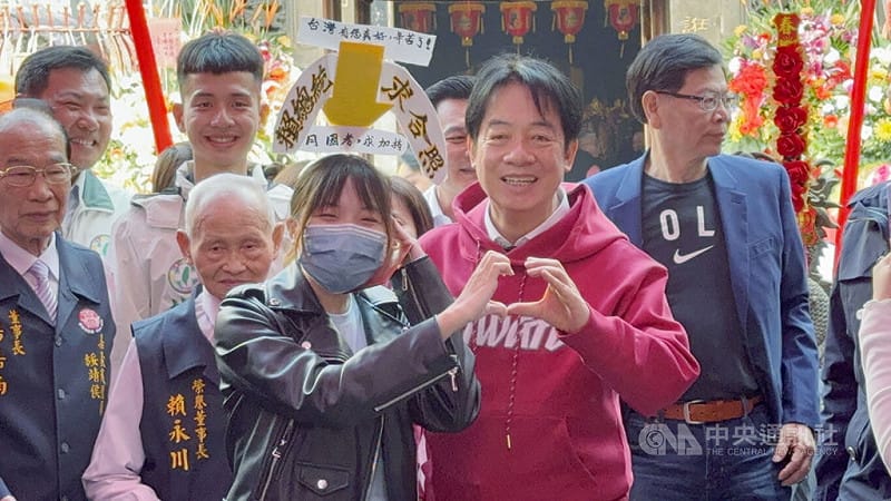 總統賴清德（紅衣者）17日到嘉義市城隍廟參拜祈福，隨後發放福袋給民眾，有民眾帶著自製道具與賴總統合照。&nbsp;&nbsp;&nbsp;圖：中央社提供