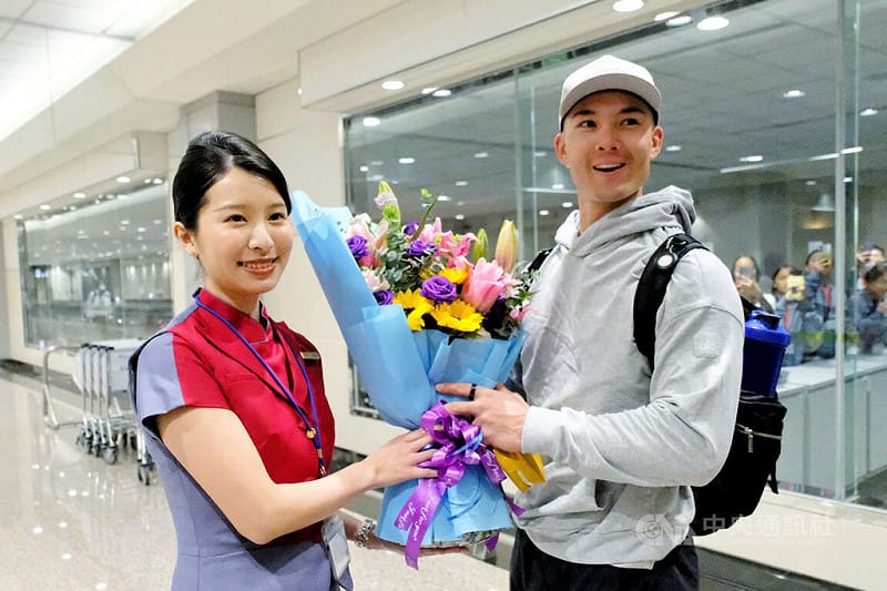 台美混血棒球好手費柴德（Stuart Fairchild）（右）26日晚間搭機順利抵達桃園國際機場，27日就會參與經典賽台灣隊練球，華航地勤人員在機場獻花表達歡迎之意。 &nbsp;&nbsp;&nbsp;圖/中央社
