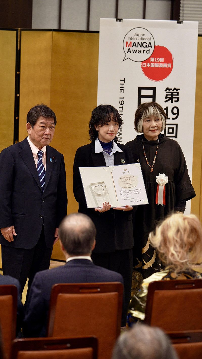 台灣漫畫家南南日（中）手持獎狀與日本外務大臣茂木敏充（左）、評審長里中滿智子（右）合影&nbsp;&nbsp;&nbsp;圖：台灣文化中心提供