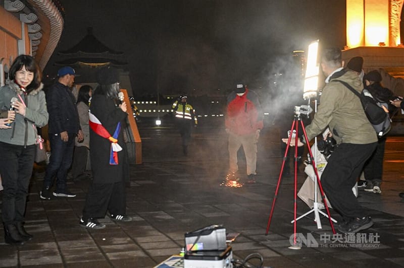 西藏抗暴67週年，在台藏人團體10日晚間在台北自由廣場舉行燭光晚會，不過現場一名男子（後右紅衣者）活動中突然扔擲鞭炮，地面一度爆出火花與煙霧，引發關注。&nbsp;&nbsp;&nbsp;圖：中央社