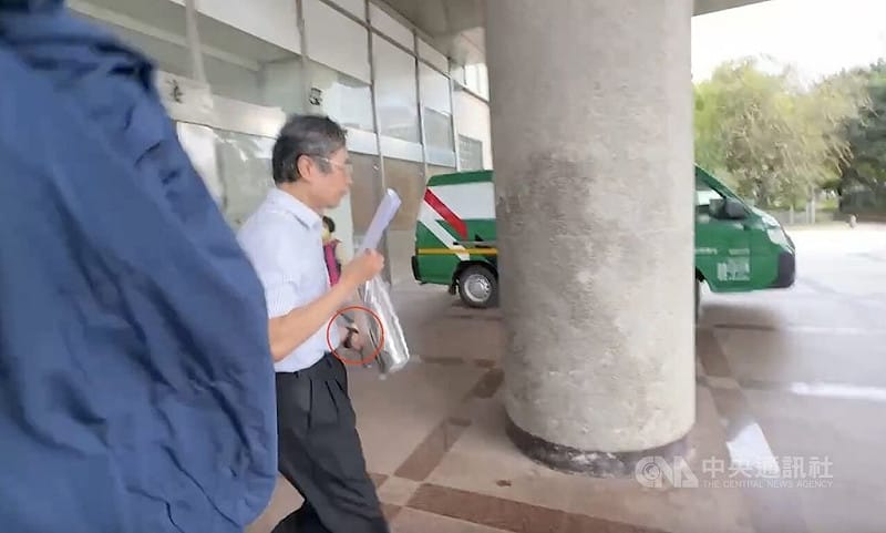 苗栗縣頭份市邱姓男醫師性騷診所女員工涉強制猥褻罪遭聲押，法院1日凌晨裁定以新台幣30萬元交保並實施科技監控。邱男下午步出法院時，左手已戴上黑色監控手環（紅圈處），一見媒體立即快閃。（翻攝畫面）中央社記者管瑞平傳真　115年4月1日&nbsp;&nbsp;&nbsp;