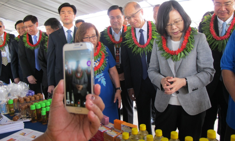 總統蔡英文與馬紹爾總統海妮31日參訪「一島嶼一特產」手工藝品展示會，小販拿起手機拍照。   圖：林朝億/攝