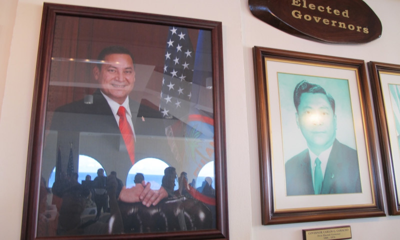 關島總督府大廳放有指定及民選等歷任總督照片；圖左為現任總督卡佛的照片。   圖：林朝億/攝