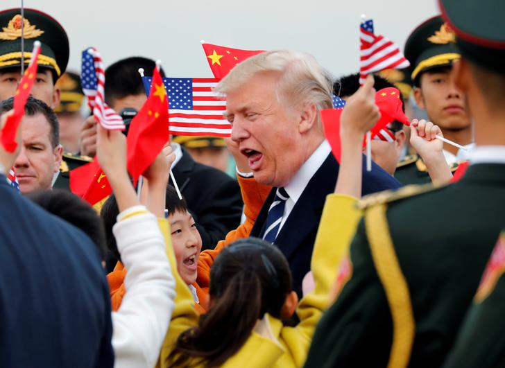 川普夫婦下機後，熱情的中國民眾代表夾道歡呼致意，幾乎快被中美兩國小國旗和人潮淹沒，川普看似相當興奮。   圖：達志影像/路透社