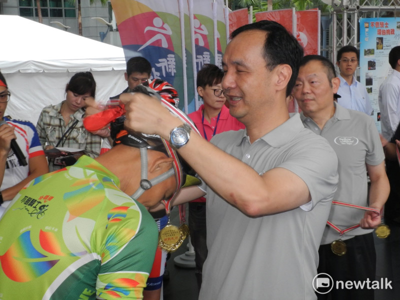 新北市長朱立倫為台灣抗癌協會46位癌友，一一掛上環台成功金牌，祝賀他們完成10天1100公里單車環台的艱鉅任務。   圖：王峻昌/攝
