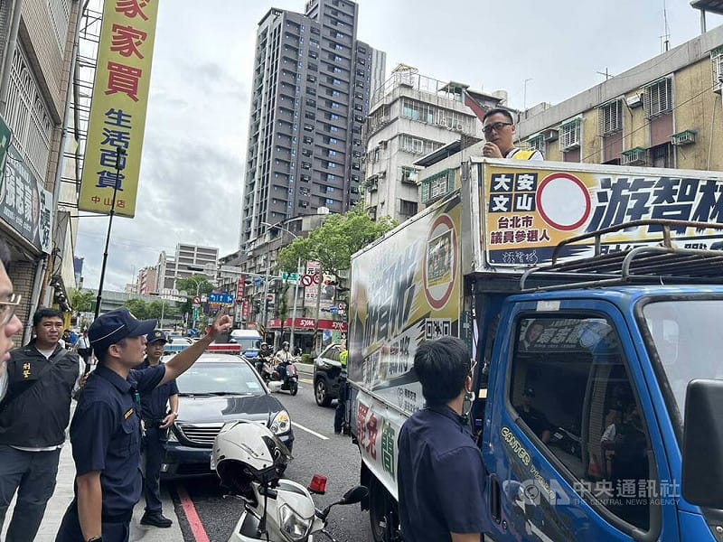 新黨台北市議員參選人游智彬（車上）25日搭著宣傳車到民進黨新北市議員參選人張志豪服務處抗議，還一度扔擲雞蛋，中和警分局獲報到場實施預防性部署與安全維護，後續並將游智彬依毀損現行犯帶回偵訊。（翻攝畫面）中央社記者曹亞沿傳真　115年8月25日&nbsp;&nbsp;&nbsp;