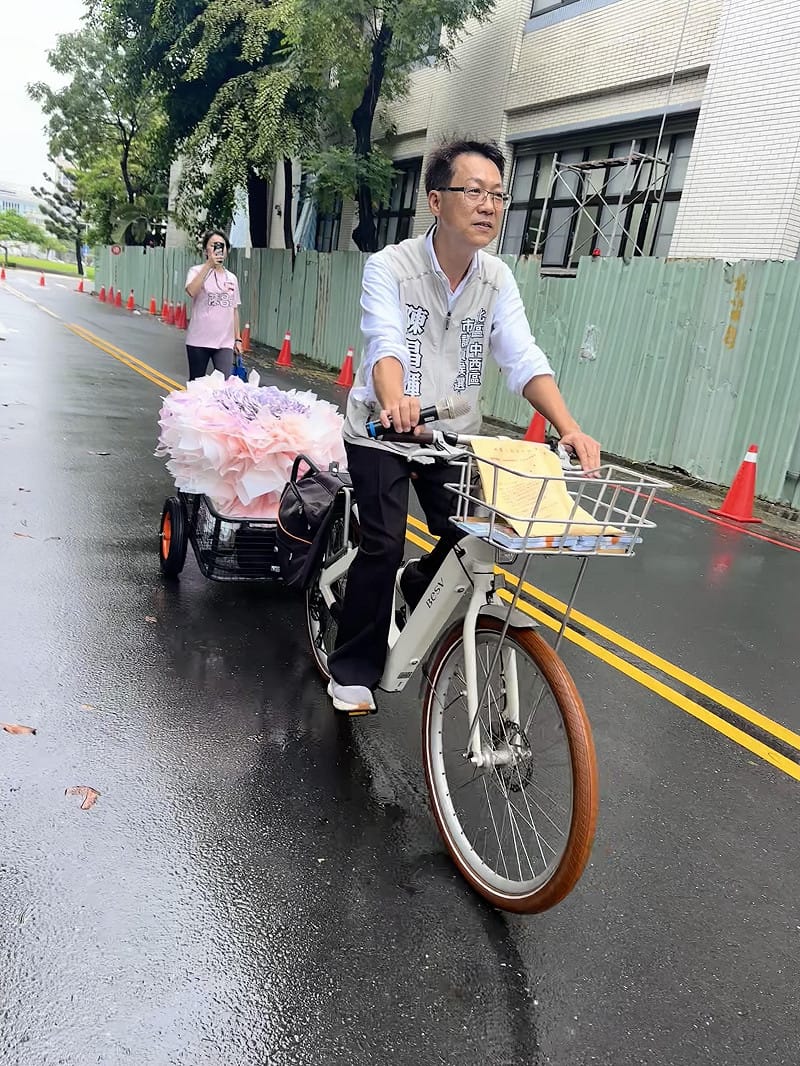 陳昌輝騎乘三輪車載著由80張兩千元鈔票打造的「有錢花」花束現身，並手棒花束向選委會繳交保證金。&nbsp;&nbsp;&nbsp;圖：黃博郎／攝