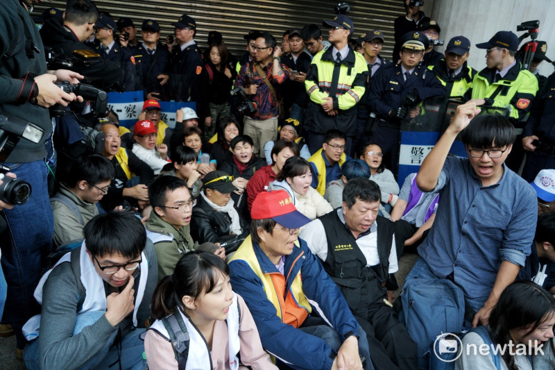 抗議人士包含勞工團體與學生在內手勾手席地而坐，佔領群賢樓前樓梯不願離開，目前警方與抗議人士仍在僵持中。   圖：張良一/攝