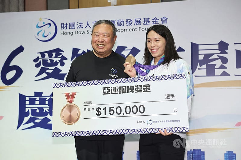 「舉重女神」郭婞淳（右）在名古屋亞運女子61公斤級獲得銅牌，5日出席宏道運動發展基金會慶功餐會，獲董事長林鴻道（左）頒發新台幣15萬元獎金。中央社記者王飛華攝　115年10月5日&nbsp;&nbsp;&nbsp;