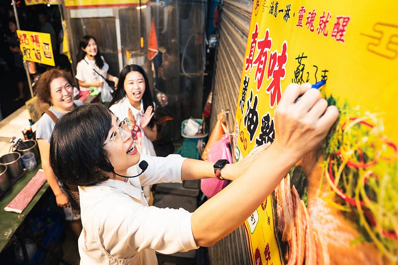 夜市攤商請蘇巧慧在店名海報上簽名。&nbsp;&nbsp;&nbsp;圖：蘇巧慧競總提供