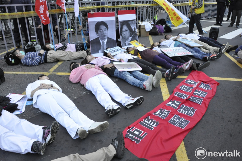 來自各地的醫護人員平躺在立法院群賢樓外，抗議、呈現過勞後的處境。   圖：陳香蘭／攝