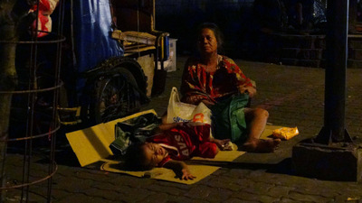 馬尼拉市一群流浪三輪車夫，白天載客謀生，晚上就把三輪車停上人行道，當作自己的家。圖為一名老婦在三輪車旁哄孫兒入睡   圖 : 中央社