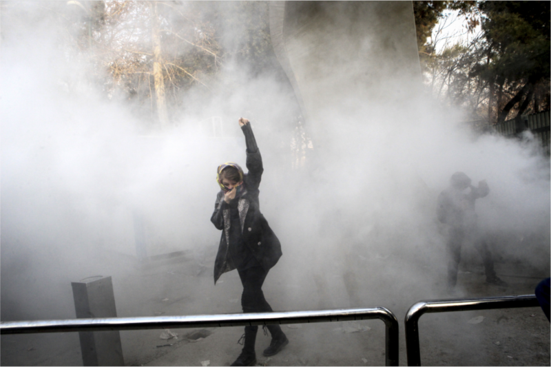 德黑蘭大學一名男學生被鎮暴部隊的煙霧彈困住，但仍振臂高呼反伊朗政府口號。   圖：達志影像/美聯社