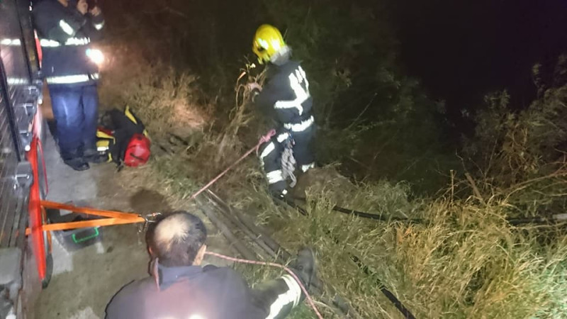一輛載運斷木的拖板車26日晚間翻落18米深河谷，屏東縣消防局接獲報案後，派員前往救援。   圖：屏東縣消防局提供