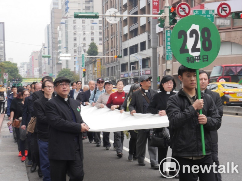 遊行民眾手持30年前，鄭南榕以「和平紀念日」方式，發起「二二八真相平反運動」的告示牌。   圖：趙婉淳／攝
