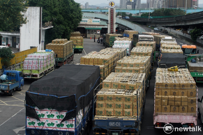 台北農產公司第一拍賣市場外擠滿了四條長龍的載運蔬菜的大貨車，等待進入拍賣場。由於擔心太晚到蔬菜無法拍賣，許多貨運司機凌晨一點多就在拍賣場外卡位。   圖：張良一 / 攝