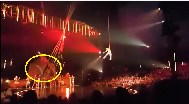 太陽劇團空中飛人阿諾德（黃圈處）在4.6公尺高空表演時失手墜地，現場一片驚呼。   圖：翻攝ÇapaMag Moments推特