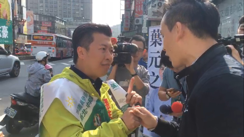 張志豪、葉元之兩位藍綠前發言人，今早站路口時「巧遇」激辯，還握手相互加油。   圖：王峻昌/翻攝