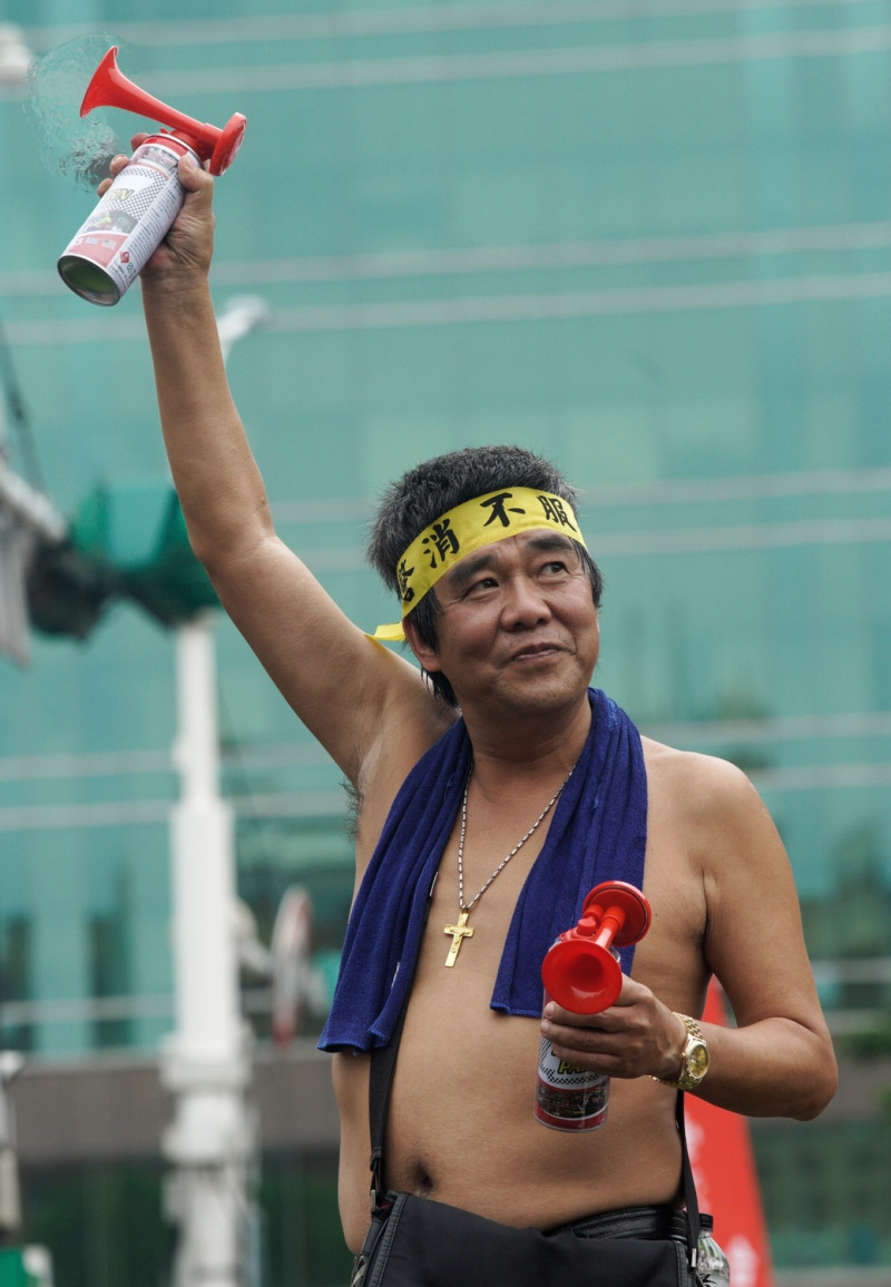 民眾赤裸上身拿著造勢喇叭參加遊行活動。   圖：張良一/攝