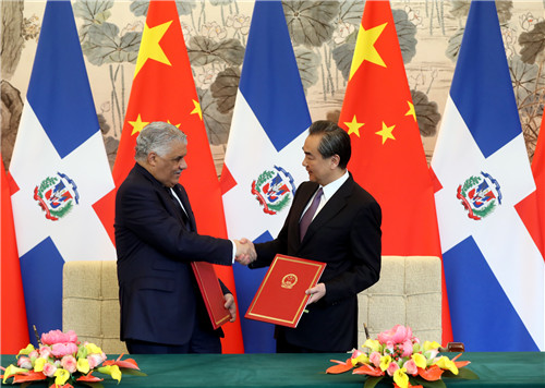 聯合公報並稱，「中華人民共和國政府和多明尼加共和國政府商定，將根據1961年《維也納外交關係公約》規定和國際慣例，儘早互派大使，並在對等基礎上在各自首都為對方設立使館和履行職務提供一切必要的協助」。圖右為中國國務委員兼外交部長王毅，多明尼加外長瓦爾加斯（左，Miguel Vargas Maldonado）則於簽約後與他握手致意。   圖：翻攝自中國外交部網站