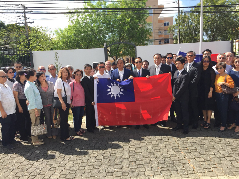 中華民國與多明尼加斷交後，駐多明尼加大使館於當地時間1日下午，舉行降旗典禮，使館人員與當地僑胞與降下的國旗合影。   圖：僑委會提供