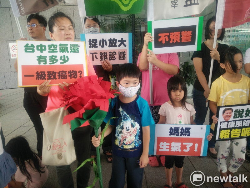 媽媽們帶著小朋友拿著超大朵康乃馨，在台中市政府廣場抗議市府不公布報告。   唐復年/攝