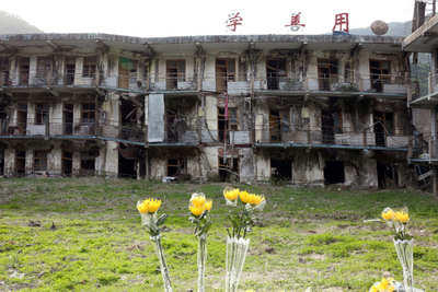 四川北川還保留2008年地震時破損的房屋。5月初，在北川職業中學遺址前，當年的師生結伴悼念遇難者，留下鮮花。   圖/中新社