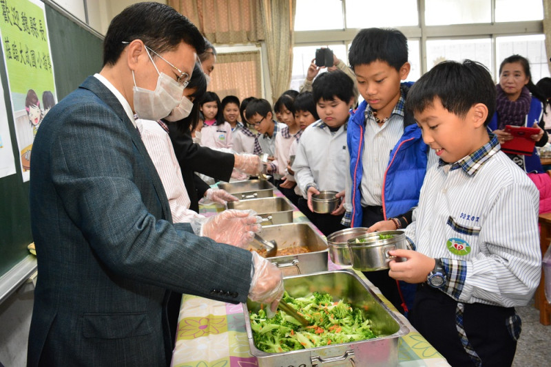 綠能午餐計畫說明會，縣長魏明谷為學童打菜。   圖：彰化縣教育處/提供