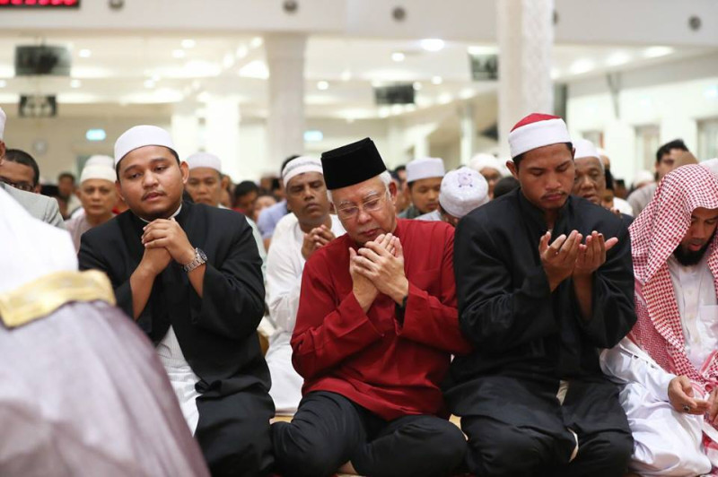 馬來西亞前總理納吉布（中）16日晚間在臉書po出自己做晚禱照片，未料即傳出他的5處據點遭到警方同步搜索。   圖：翻攝納吉布臉書