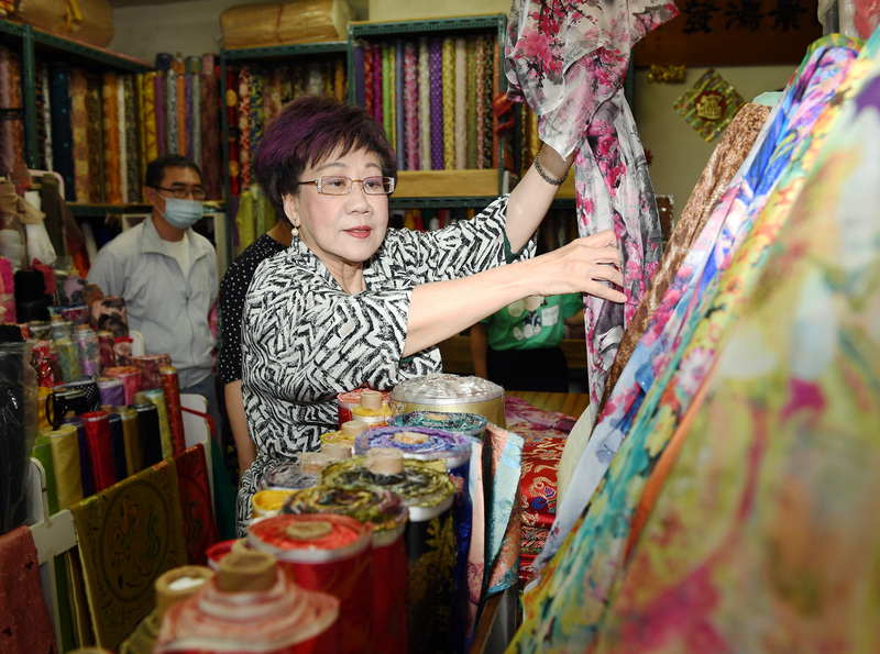 前副總統呂秀蓮（中）19日前往台北迪化街，參訪多家布莊，對台灣服飾仔細詢問並採購衣料。   圖：中央社