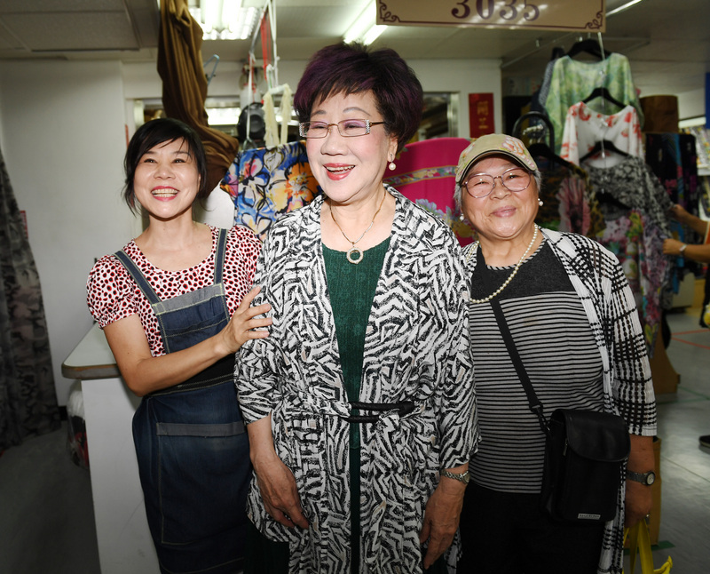 前副總統呂秀蓮（中）19日到台北迪化街參訪多家布莊，對台灣服飾仔細詢問、採購衣料，並與熱情民眾合影。   圖：中央社
