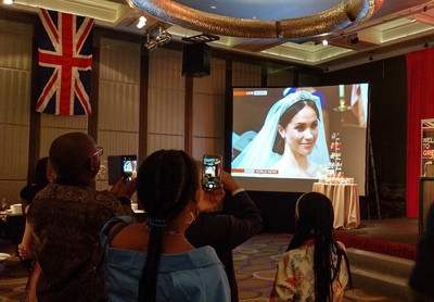 英國在台辦事處19日在台北舉辦英國王子哈利與新娘梅根馬克爾皇家婚禮的慶祝酒會，現場轉播婚禮實況，不少人拿出手機記錄歷史一刻。   圖：中央社