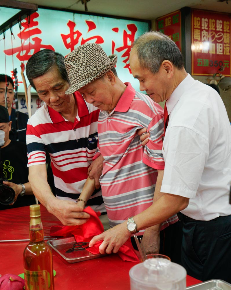 亞洲蛇肉店的董事長郭來貢（中）和殺蛇師傅洪丁福（左）共同將一把使用數十載，殺蛇無數的剪刀封刀。   圖：張良一/攝