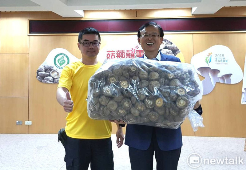 首次參賽就拿首獎成為「菇王」的江文棋（左），他的5斤裝香菇，最後以15萬元拍賣價成交；板農理事長廖裕德特地鼓勵他。       圖：王峻昌/攝 
