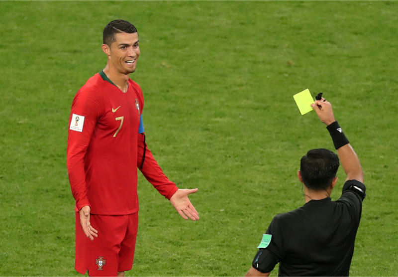葡萄牙王牌「C羅」羅納度（Cristiano Ronaldo，左）在小組賽前2戰共踢進4球，包辦全隊所有進球，今天他被對手鎖死、幾乎沒有太多進攻機會。圖為C羅犯規拿了一張黃牌，兩手一攤，露出尷尬一笑。   圖：達志影像/路透社