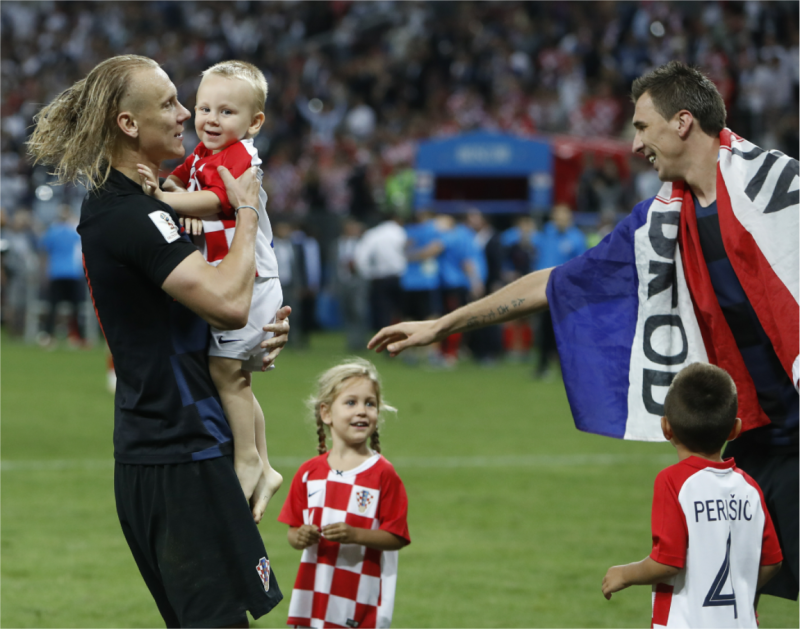 在延長賽以左腳奇襲攻進致勝關鍵球的克羅埃西亞英雄曼祖基奇（Mario Mandzukic，右）, 在球隊逆轉擊退英格蘭賽後，披上克羅埃西亞國旗，與隊友維達（Domagoj Vida ）及他們可愛的孩子，一起在球場內開心慶祝。   圖：達志影像/美聯社