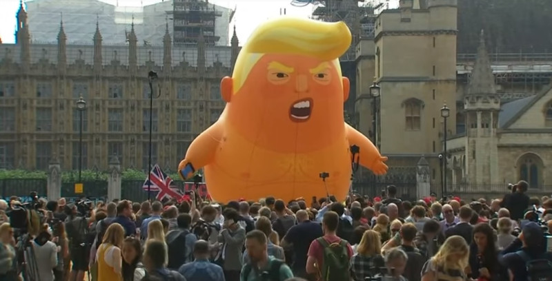 半裸的巨嬰川普氣球包著尿布，右手還拿著手機，諷刺川普是「推特總統」。   圖：翻攝Youtube