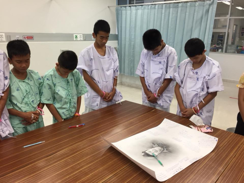 泰國足球少年獲知前海豹隊員沙曼為救他們而犧牲，圍在畫像前默哀。   圖：翻攝泰國公共衛生部臉書