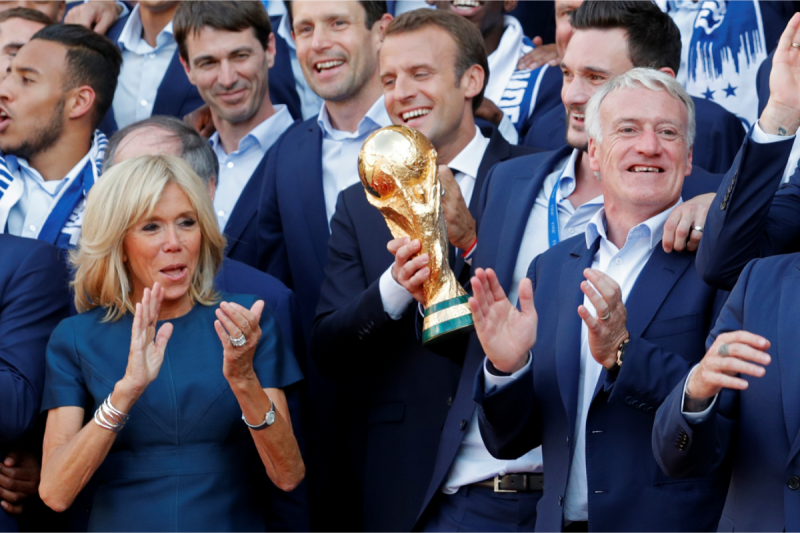 法國總統馬克宏（Emmanuel Macron）和夫人碧姬（Brigitte Macron，左）兩人16日在巴黎愛麗舍宮（Elysee Palace），為載譽歸國的國家足球隊舉行致敬接待會，與隊長洛里斯（Hugo Lloris，右2 ）、總教練德尚（Didier Deschamps，右1）及其他「國腳」們談笑風生 。馬克宏手握大力神盃，狀甚興奮。   圖：達志影像/路透社
