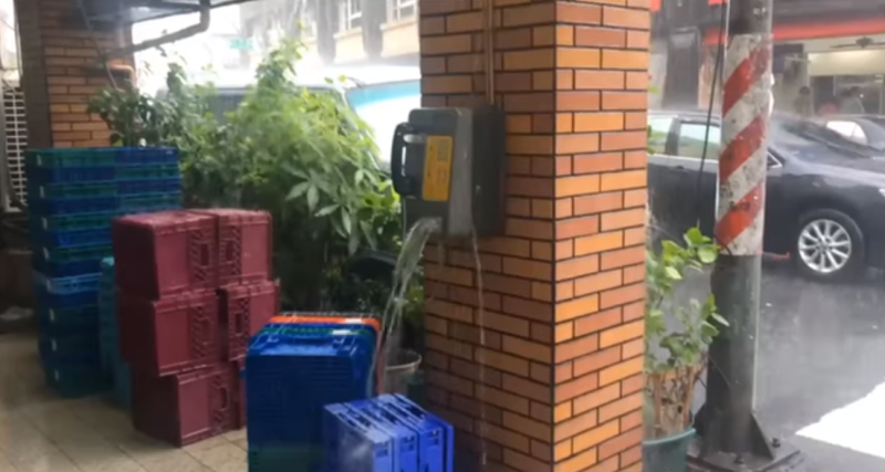 高雄一家超商外電話亭由於豪雨影響，竟化身成迷你瀑布。   圖：翻攝黑色豪門企業臉書