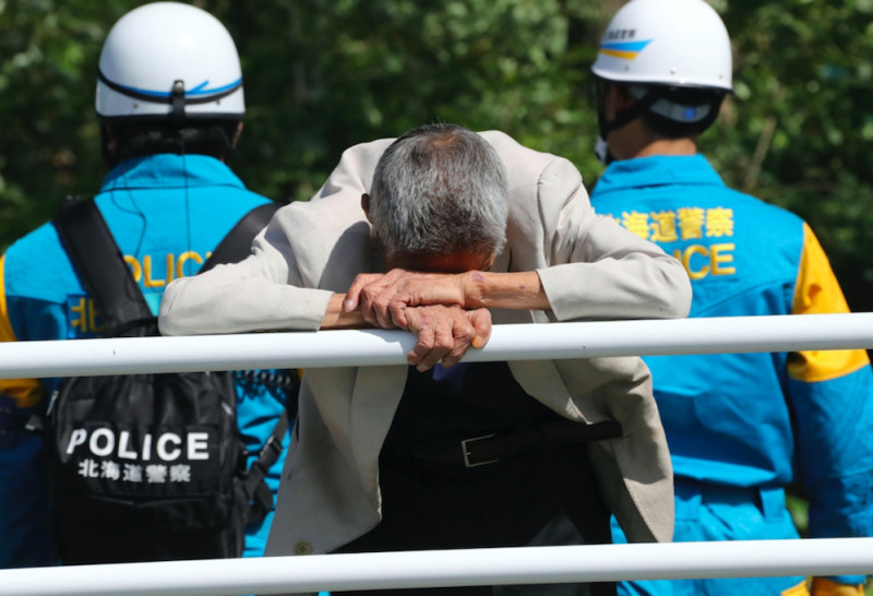 北海道大地震，一名男子趴在鐵桿上，對未來感到茫然。   圖：達志影像/美聯社