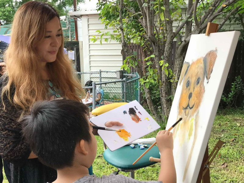 旅美藝人畫家張富美現場示範及指導小朋友，如何生動繪出狗狗的可愛神韻。                          
   圖：新北市動保處提供                        